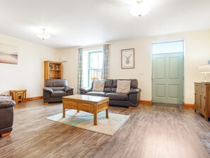 A living room with two leather sofas, a wooden coffee table, a wooden cabinet, and a door. - 3 bedroom accommodation in Arnside and Silverdale (Arnside and Silverdale)