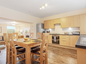 A modern kitchen with wooden cabinets, a dining table with chairs, and a built-in oven. - 3 bedroom accommodation in Arnside and Silverdale (Arnside and Silverdale)
