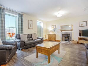 A living room with a leather sofa, a wooden coffee table, a fireplace, and a television. - 3 bedroom accommodation in Arnside and Silverdale (Arnside and Silverdale)