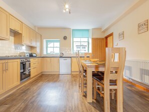 Eine moderne Küche mit Holzausbau, einem Geschirrspüler und einem Essbereich mit Holztisch und Stühlen.