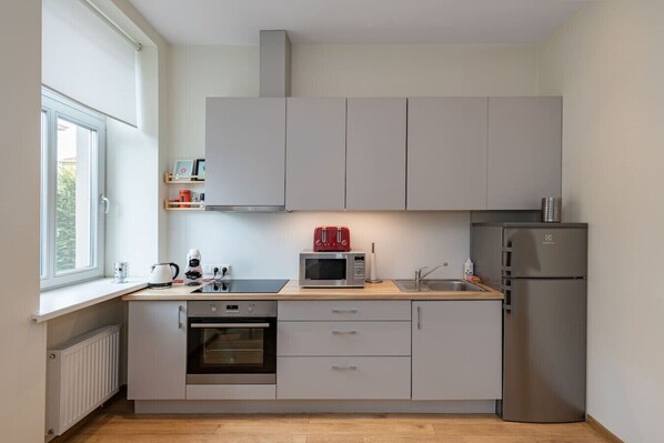 Una cocina moderna con horno empotrado, microondas y refrigerador de acero inoxidable.