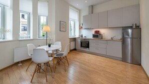 A modern kitchen with a dining area, large windows, and a refrigerator.