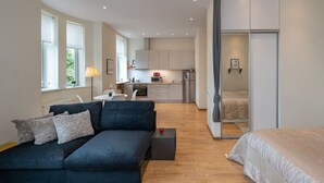 A modern apartment with a living area, kitchenette, and a bedroom with a sliding door.