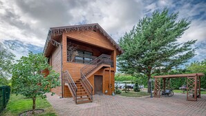 A wooden cabin with a balcony, a staircase, and a garden area. - Calm and private ap by Polo Apartments (Kaunas)