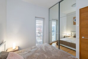 Makuuhuoneessa on sänky, yöpöytä, peilipöytä, peili ja liukuovet, jotka johtavat parvekkeelle.