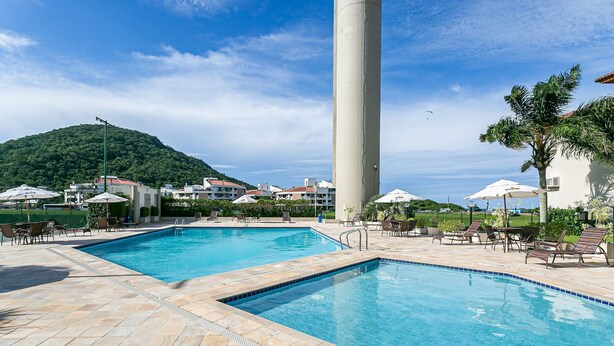 A swimming pool area with two pools, lounge chairs, and umbrellas. - 200m from Beach | Bbq Grill | Swimming Pool #IA29 (Florianópolis)