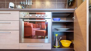 Una cocina compacta con horno integrado, un lavamanos pequeño y un armario de almacenamiento.