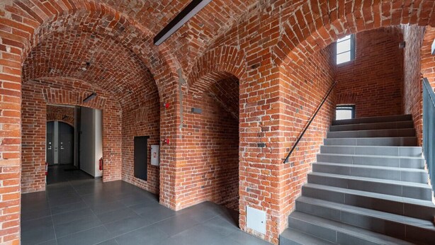 A spacious interior with brick arches, a staircase, and a tiled floor. - Shanti barracks ap by Polo apartments (Kaunas)