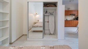 Quarto com cama, guarda-roupa e tábua de passar roupa.