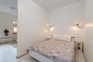 Une chambre à coucher comprenant un lit, des tables de chevet, une commode et une fenêtre donnant sur un paysage agréable.