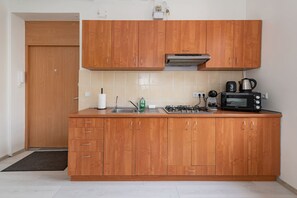 Une cuisine avec des meubles en bois, une cuisinière à gaz, un four à micro-ondes et une bouilloire.