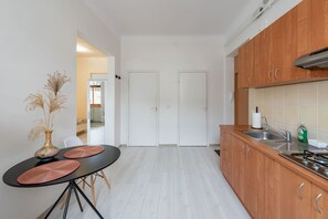 Une cuisine moderne avec des meubles en bois, une table à manger avec des sets de table et un vase contenant des plantes séchées.