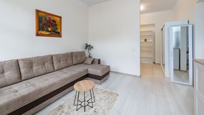 Uma sala de estar moderna com um sofá seccional, um banquinho de madeira, uma planta em vaso e um quadro na parede.