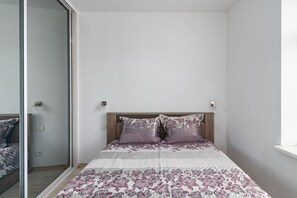 Quarto com cama, espelho e janela.