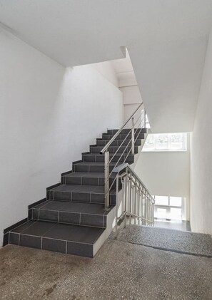 A staircase with a metal railing, leading to a higher floor. - Nemunas River View by Polo Apartments (Kaunas)