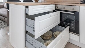 A modern kitchen with white cabinetry, a wooden countertop, and a built-in oven.
