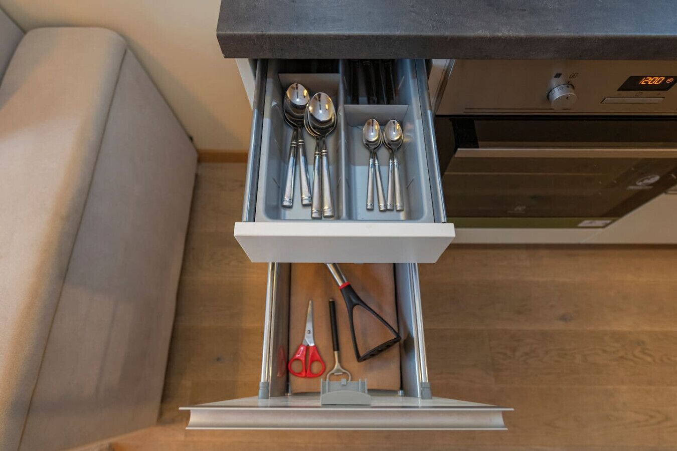 Un cajón de cocina con utensilios y un reloj digital.