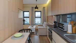 A compact kitchen with a dining area, a sofa, and a view of the outside.