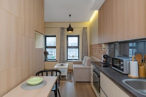 A compact kitchen with a dining area, a sofa, and a view of the outside.