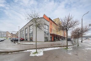 A building with multiple storefronts, a parking lot, and leafless trees.