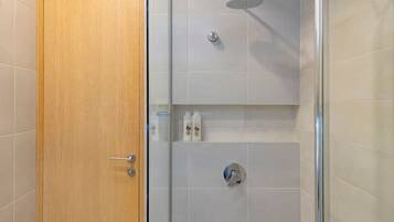 Un baño moderno con puerta de madera, cabina de ducha de vidrio y paredes con azulejos.