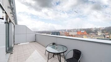 Ein Balkon mit Fliesenboden, einem Glastisch und zwei Stühlen.