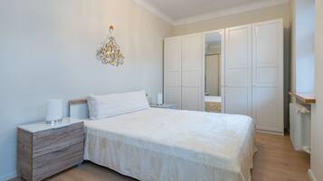 A bedroom with a bed, bedside tables, a dresser, a wardrobe, and a decorative wall piece.