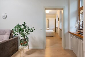 Um corredor com uma planta, uma cama e um modelo de navio.