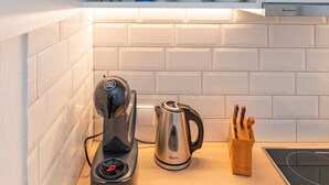 A kitchen with a coffee maker, kettle, and knife block on the counter.