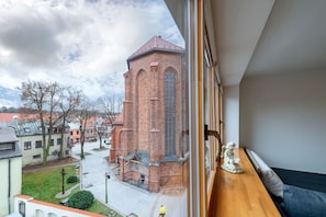 A room with a view of a brick building, a window sill, and a statue.