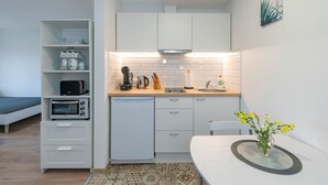 A compact kitchen with white cabinets, a microwave, a toaster, a sink, and a small dining area with a table and chair.