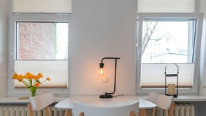 Une table ronde avec quatre chaises, un lampadaire et un vase de fleurs.