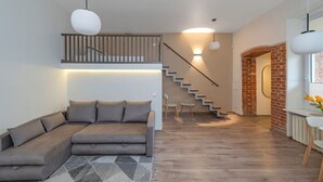 Un salon moderne avec un canapé, un escalier et un mur en briques.