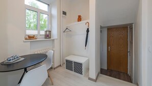 A small, bright room with a table, chairs, a radiator, a door, and a window.