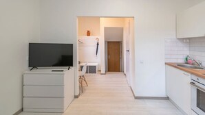 A compact kitchen with a TV, a small table, and a door leading to another room.