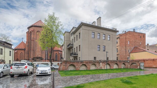 A street with a church, a multi-story building, and parked cars.