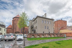 A street with a church, a multi-story building, and parked cars.