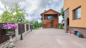 A two-story building with a wooden facade, a stone wall, and a paved driveway. - Spacious Studio ap by Polo apartments (Kaunas)