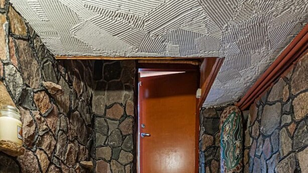 A stone wall, wooden steps, a wooden door, and a small statue. - Spacious Studio ap by Polo apartments (Kaunas)