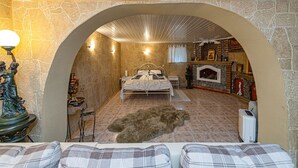 A bedroom with a stone wall, a bed, a fireplace, and a statue. - Spacious Studio ap by Polo apartments (Kaunas)