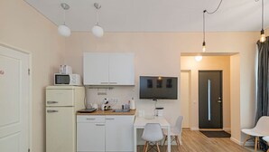 A compact kitchen with a microwave, cabinets, and a dining area with chairs and a table. - Studio ap Contrast by Polo Apartments (Kaunas)