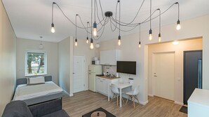 A modern room with a bed, a sofa, a desk with a computer, and a TV. - Studio ap Contrast by Polo Apartments (Kaunas)