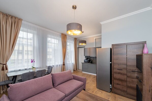 Ein modernes Wohnzimmer mit einer Couch, einem Esstisch und einer Küchenzeile.