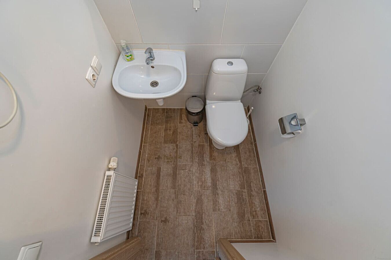 A bathroom with a sink, toilet, and radiator.