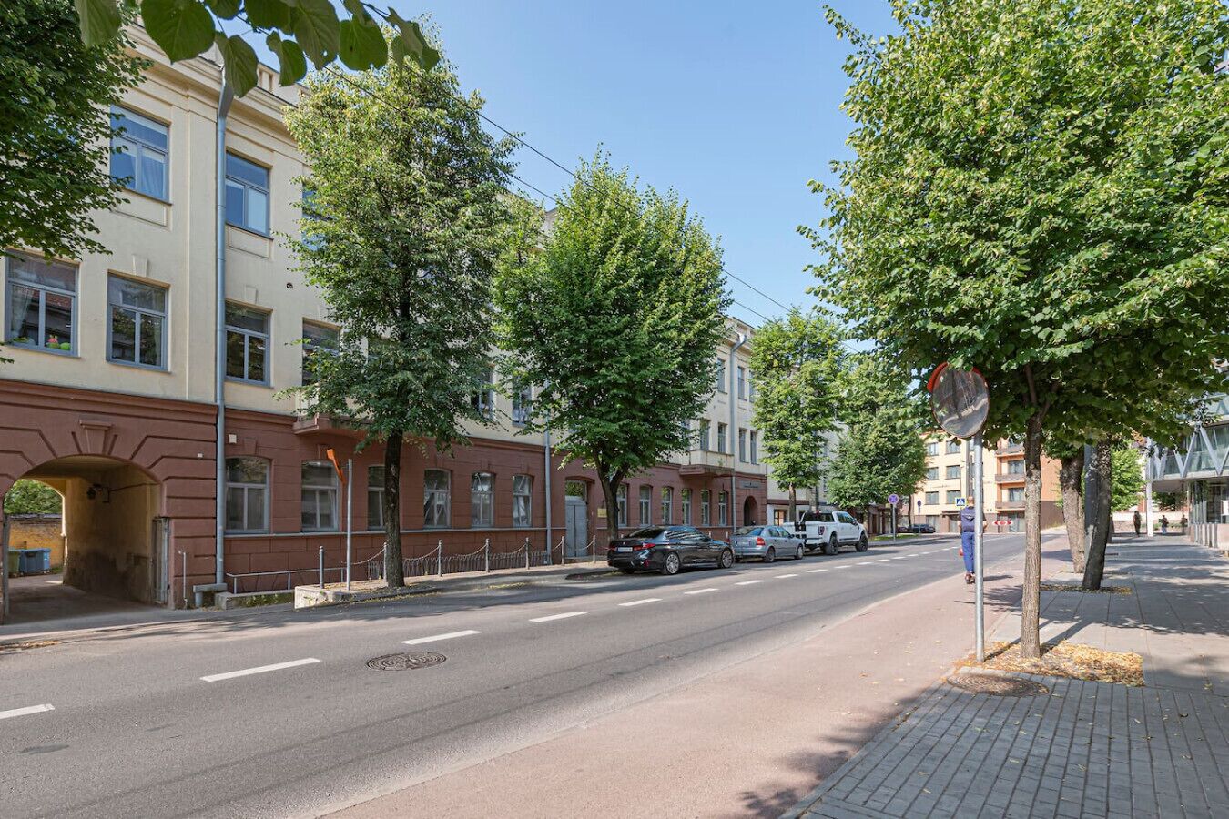 Een straat met gebouwen, bomen en geparkeerde auto's.