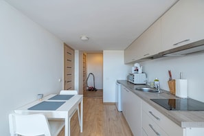 Una cocina compacta con comedor, un aspirador y un microondas.