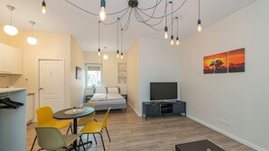 A modern apartment with a bed, a TV, a dining area, and a kitchen. - Downtown delight studio by Polo Apartments (Kaunas)