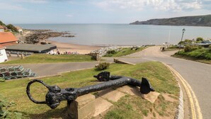 A coastal road with a large black sculpture, a grassy area, and a view of the sea. - Sunny Side (Saltburn-by-the-Sea)