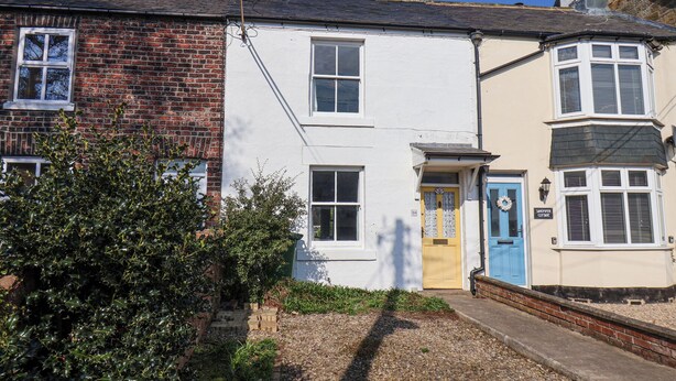 A row of terraced houses with a gravel pathway leading to the front doors.