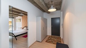 A narrow hallway with a bed, a wardrobe, and a door. - Ap Accent by Polo apartments (Kaunas)